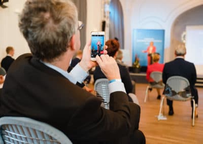 Ein Zuschauer fotografiert mit dem Handy die Rede von Bundesministerin Julia Klöckner